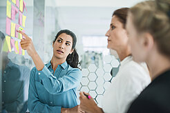 488337243 Drei Frauen diskutieren vor Pinwand